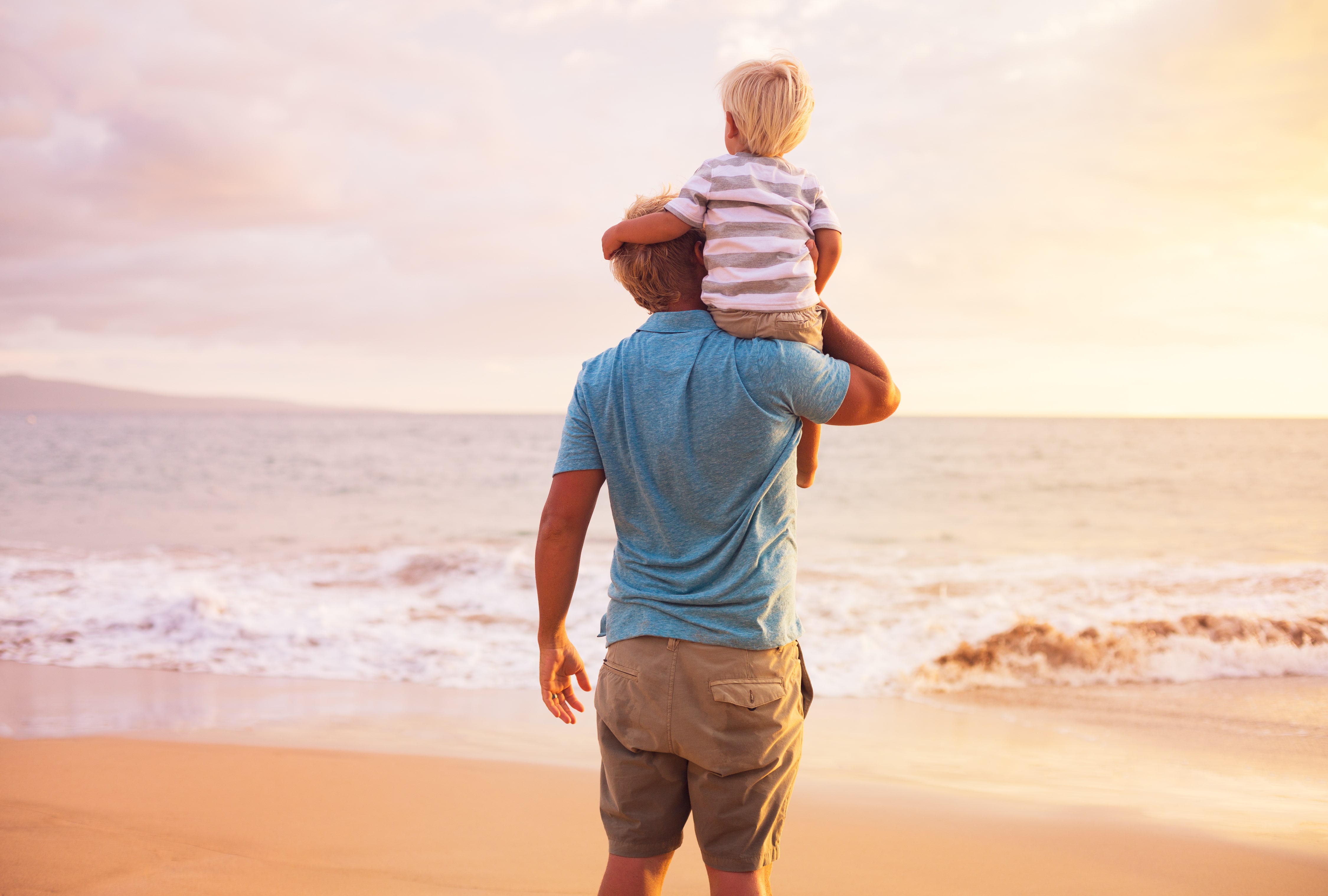 father and young son standing at the beach